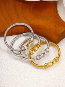 Detail of twisted cable bangles with horseshoe diamond clasp in gold and silver