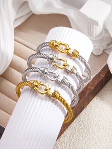 Detail of twisted cable bangles with horseshoe clasps and pavé cubic zirconia in gold