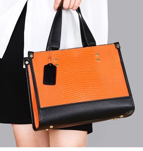 Détail du sac cabas orange à motif lézard avec des accents noirs et dorés