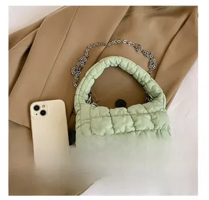 Mini light green quilted bag shown next to a smartphone for size comparison