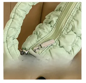 Detailed close-up of smooth silver zipper and quilted fabric on the green cloud bag