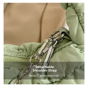Detailed close-up of the silver metal hook and quilted nylon strap on light green bag
