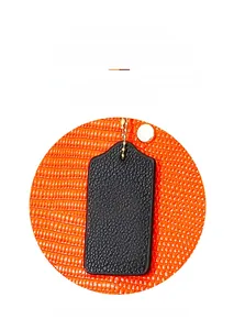 Détail de l'étiquette en cuir noir avec chaîne dorée sur un sac à motif lézard orange