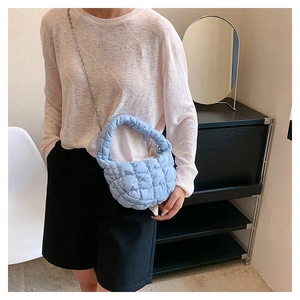 Detail of light blue quilted cloud bag with metallic chain strap and puffy texture