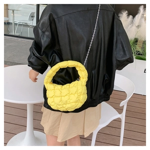 Detail view of yellow quilted puff handbag with silver chain strap and top handle