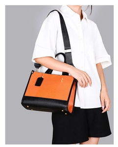 Détail du sac à main orange avec gaufrage lézard et large bandoulière en textile noir