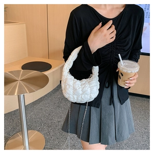 Close-up of white quilted cloud bag with puffy texture and silver metal chain strap