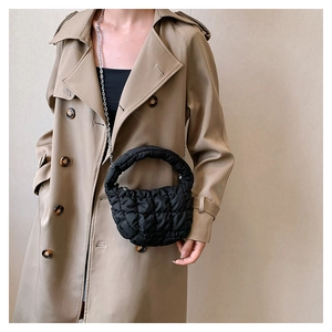 Detail of black quilted cloud bag with padded texture and silver chain strap