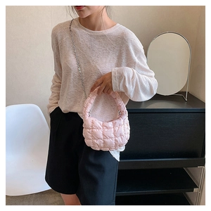 Close-up of pink quilted cloud bag featuring metallic silver chain and padded handle