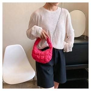 Close-up of bright pink quilted cloud bag featuring a silver metal chain strap detail