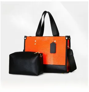 Détail du sac cabas croco orange avec pochette noire et finitions métalliques dorées