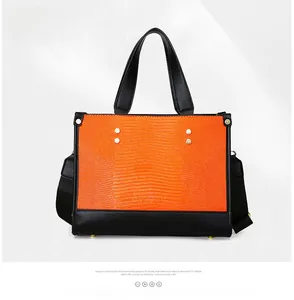 Détail du sac cabas orange gaufré avec poignées noires et clous métalliques décoratifs