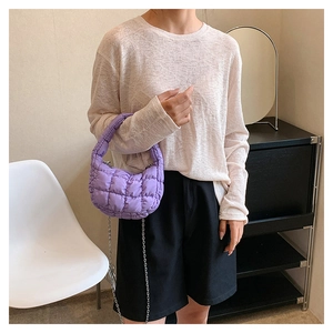 Detailed view of purple quilted cloud bag with silver chain strap on model arm