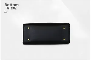 Détail du fond d'un sac à main noir en cuir grainé avec quatre pieds de protection dorés