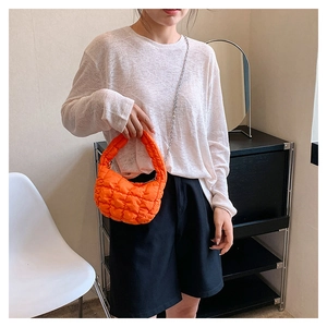 Quilted cloud bag in bright orange with puff texture and silver chain strap