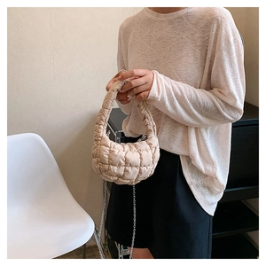 Quilted beige cloud bag with silver chain strap shown in a minimalist home setting
