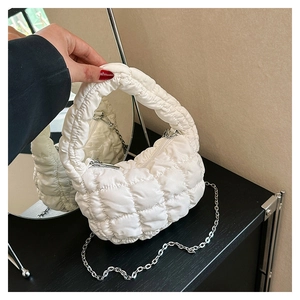 Detail of white quilted puff bag featuring silver chain strap and bubble texture
