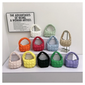 Quilted puffer handbags in various colors displayed on a modern gallery step stand