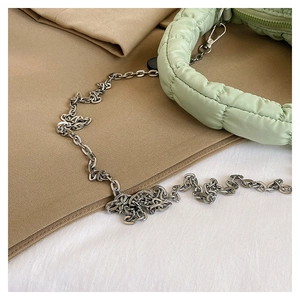 Close-up of light green quilted bubble bag with silver metal chain and soft puffy texture