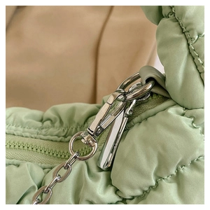Detailed close-up of quilted light green fabric and silver metal hardware of the handbag
