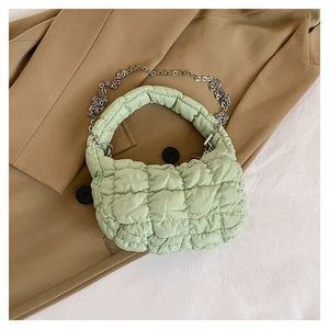 Close-up of mint green quilted cloud bag with silver chain strap on a blazer