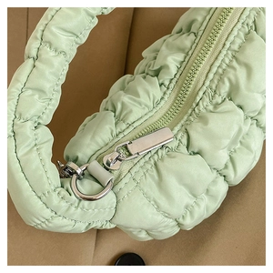 Detail view of light green quilted puffy handbag with silver ring and zipper closure