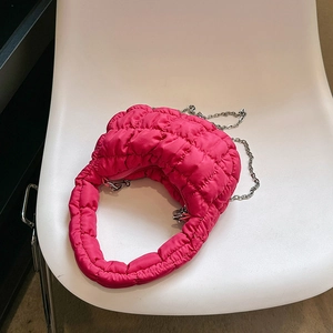 Magenta quilted cloud puff handbag with metallic chain shown on a modern white chair