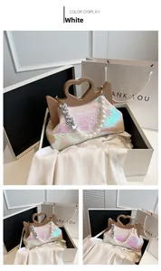 Close-up van witte tas met pailletten, bruin hartvormig handvat en parelketting