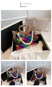 Detail van multicolor pailletten handtas met hartvormig handvat en parelketting