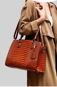 Gros plan d'un sac cabas marron à texture crocodile avec pieds de protection dorés