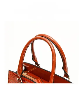 Détail d'un sac à main orange à gaufrage crocodile, fini brillant et fermeture éclair dorée
