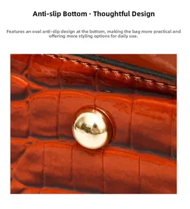 Détails des clous de protection dorés sur le sac en cuir marron-orange à motif crocodile