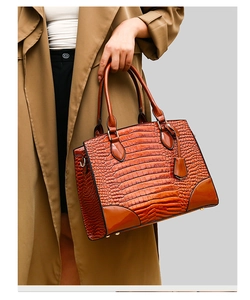 Détail du sac à main marron à motif crocodile avec double poignée et texture lisse