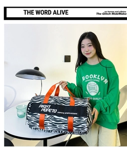 Zebra print travel duffel bag with bright orange handles shown in a lifestyle setting