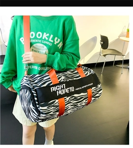 Close-up of zebra print travel bag with bright orange straps and sports logo detail