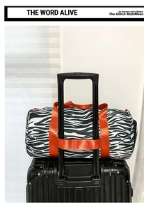 Detail of travel bag with zebra print and orange strap attached to luggage handle