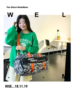 Detail view of large zebra print travel duffel bag with bright orange shoulder strap