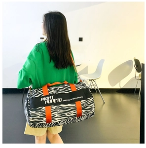 Detail of zebra print travel bag with vibrant orange straps and large capacity