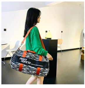 Detail of zebra print travel bag with bright orange handles and adjustable shoulder strap