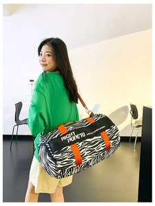 Detail of zebra print travel bag with bright orange straps and cylinder structure