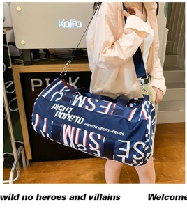 Detail of blue cylinder gym bag with all-over letter prints and adjustable strap
