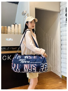 Macro detail of navy blue travel duffel bag with bold artistic letter print and sturdy strap