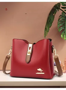 Détail d'un sac à main rouge en cuir grainé avec logo kangourou doré et finitions métal