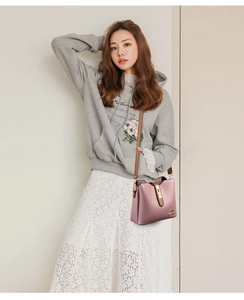 Sac seau rose avec texture litchi et bandoulière marron porté par un mannequin