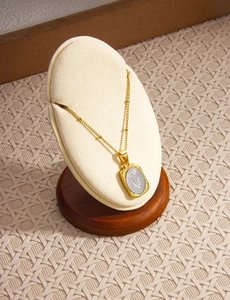 Dettaglio della collana con ciondolo floreale dorato su espositore per gioielli