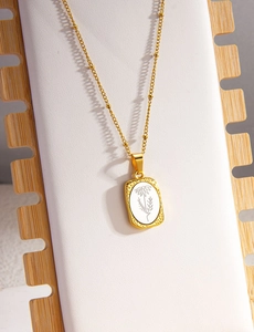 Dettaglio della collana floreale dorata con inserto bianco su espositore in pelle