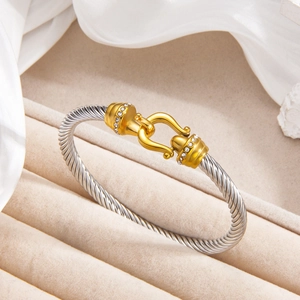 Two-tone stainless steel cable twist bracelet with gold buckle and micro-set cubic zirconia