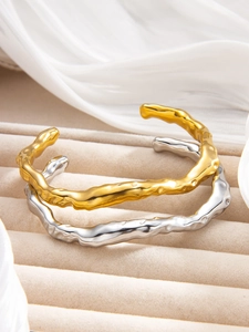 Detailed macro view of irregular organic textured C-shape bangles in gold and silver