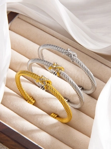 Detailed macro view of three twisted cable bracelets with crystal X motifs in a luxury box