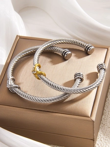 Detail of twisted cable cuff bracelets with gold X-link and crystal accents on silk